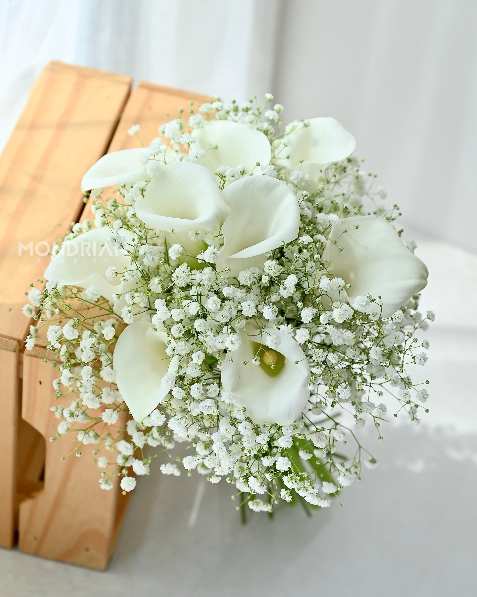 a bridal hand bouquet with fresh calla lily and baby"s breath flower