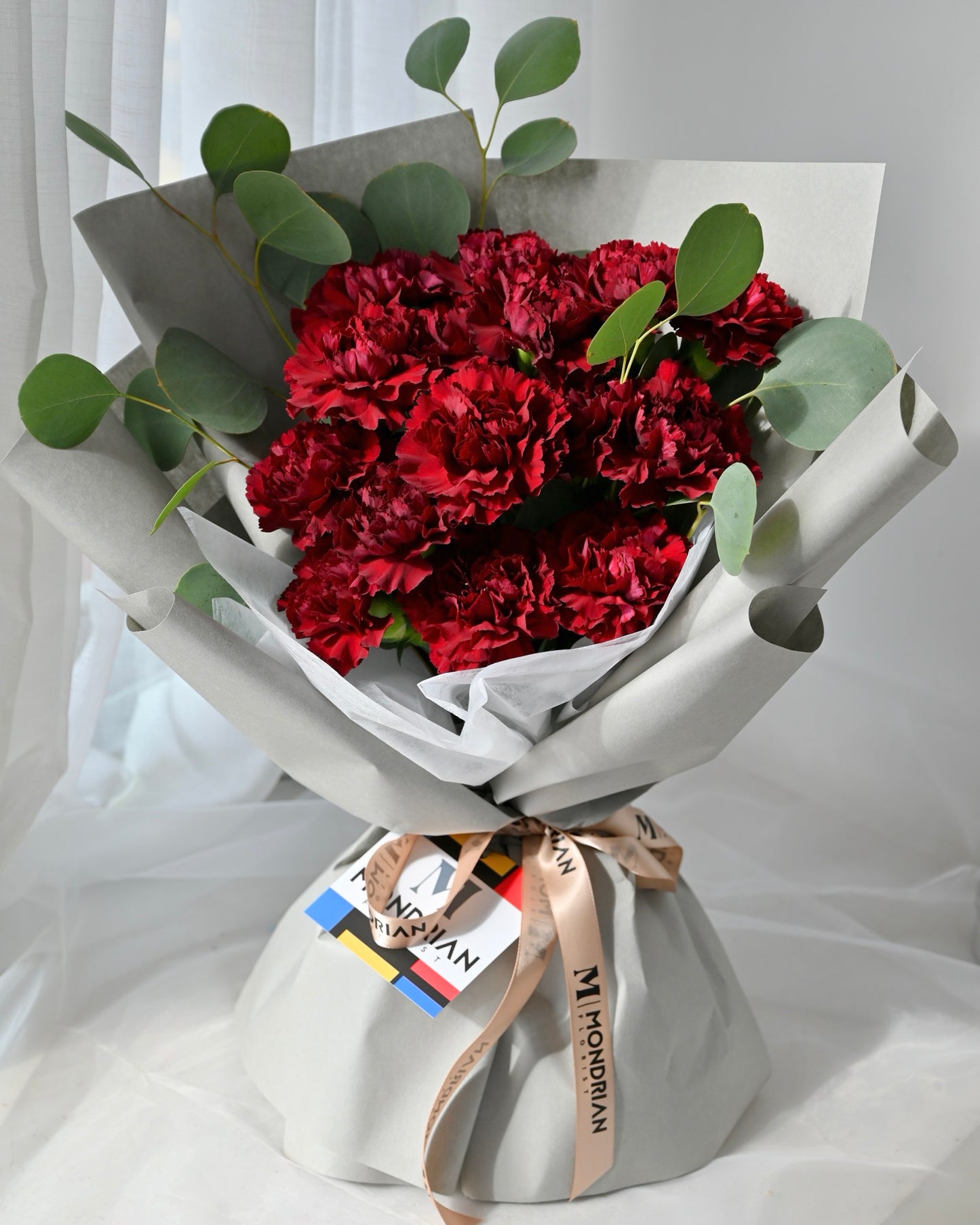 a bouquet of burgundy red carnations and eucalyptus leaves by Mondrian Florist