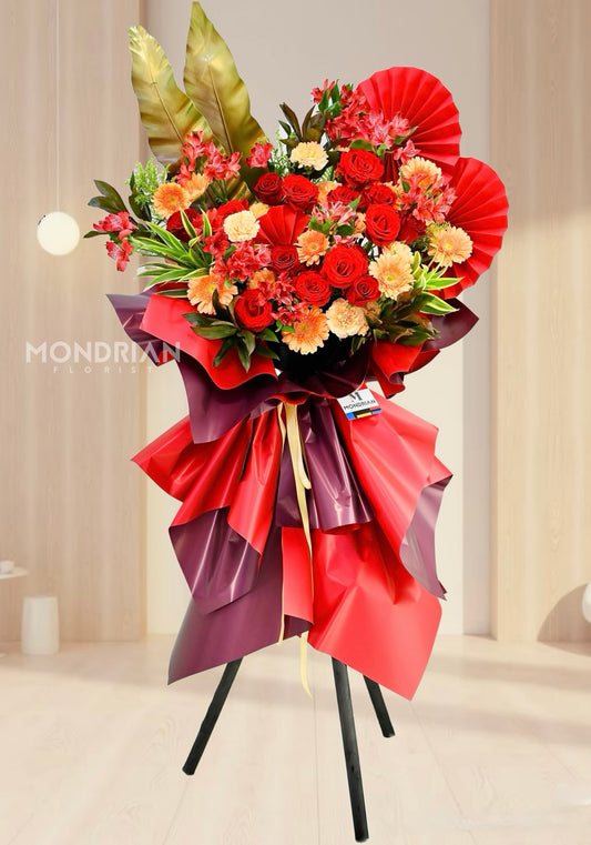 a luxury tripod shop oening flower stand with red and orange color, including roses and carnations