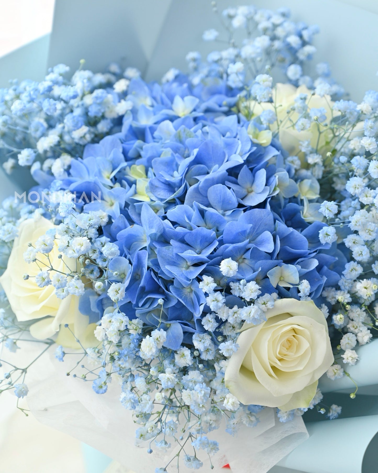 a fresh flower bouquet with blue hydrangea, white roses and baby's breath
