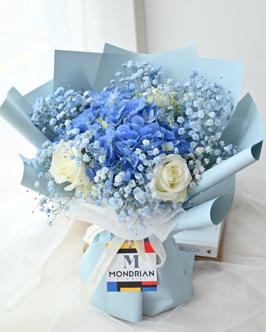 a fresh flower bouquet with blue hydrangea, white roses and baby's breath