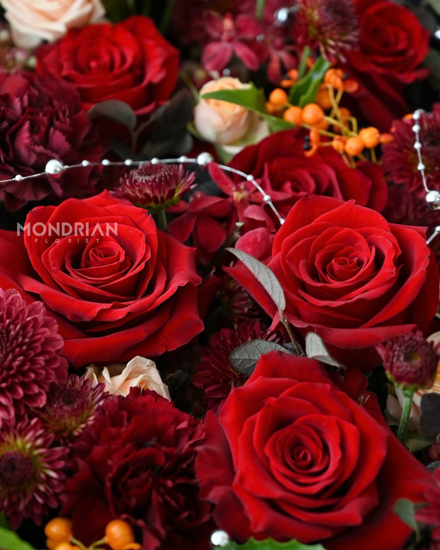 a big flower box of red roses, red carnations and filler flowers by Mondrian Florist