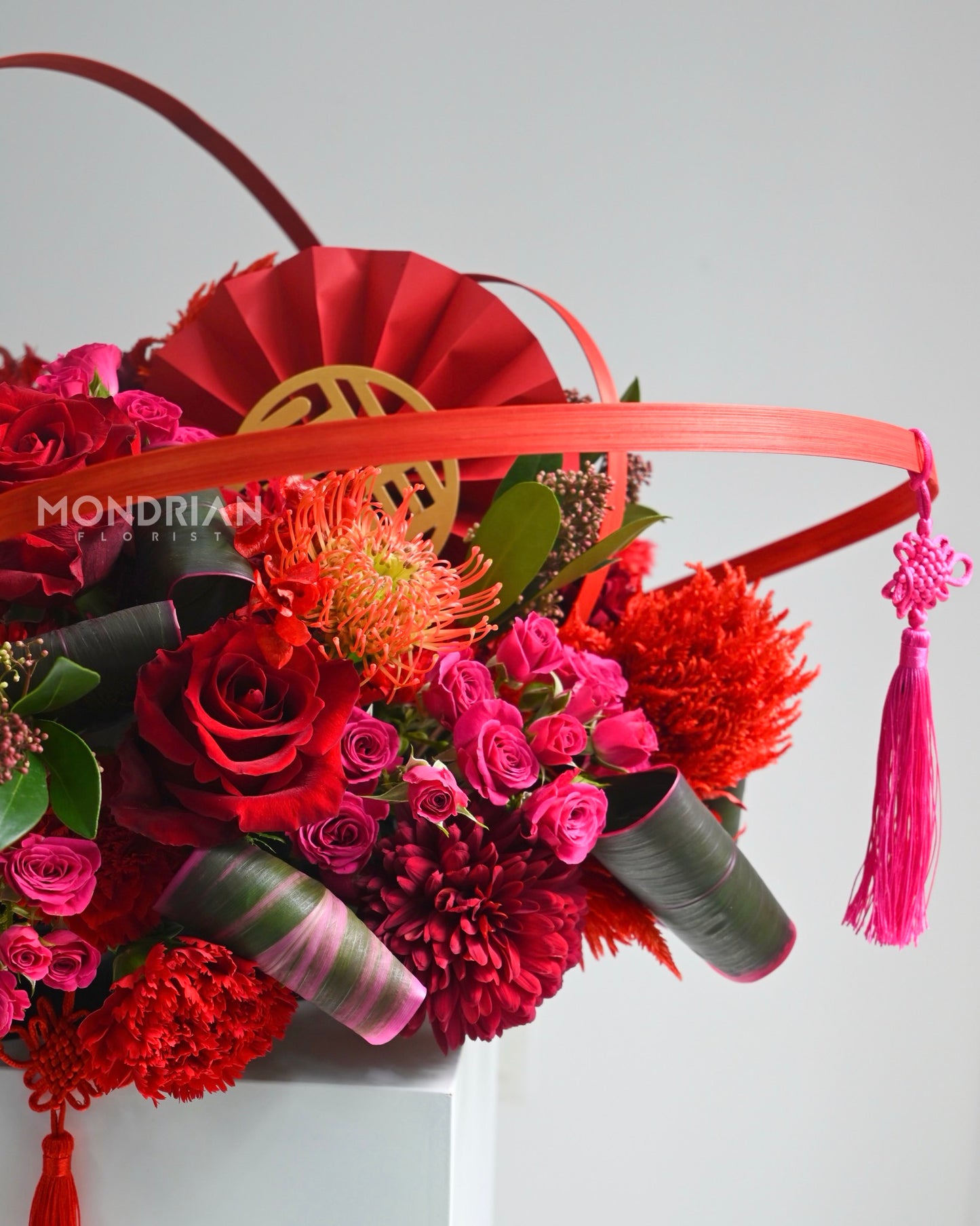 close up of a lux table arrangement of red and shocking pink roses, with chinese new year elements
