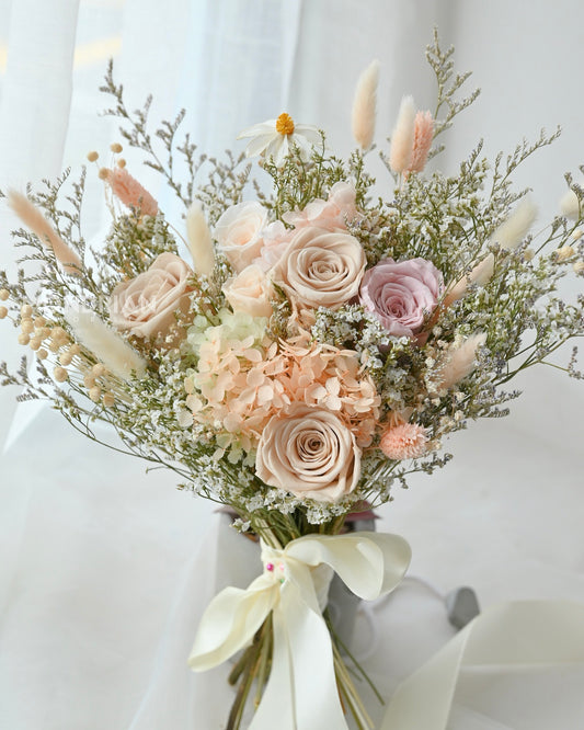 A bridal bouquet made with preserved roses and dried flowers in pastel hue.
