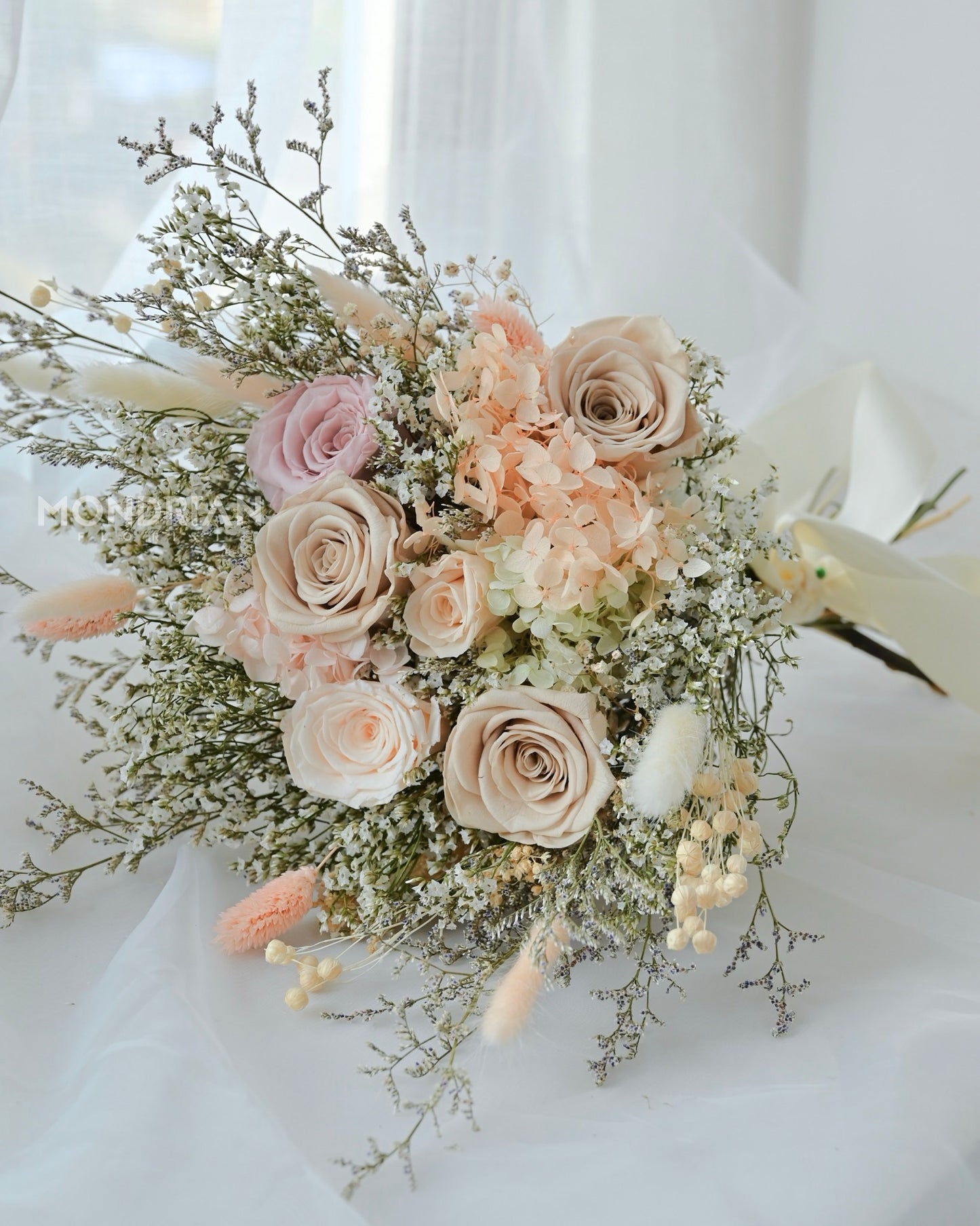 A bridal bouquet made with preserved roses and dried flowers in pastel hue.