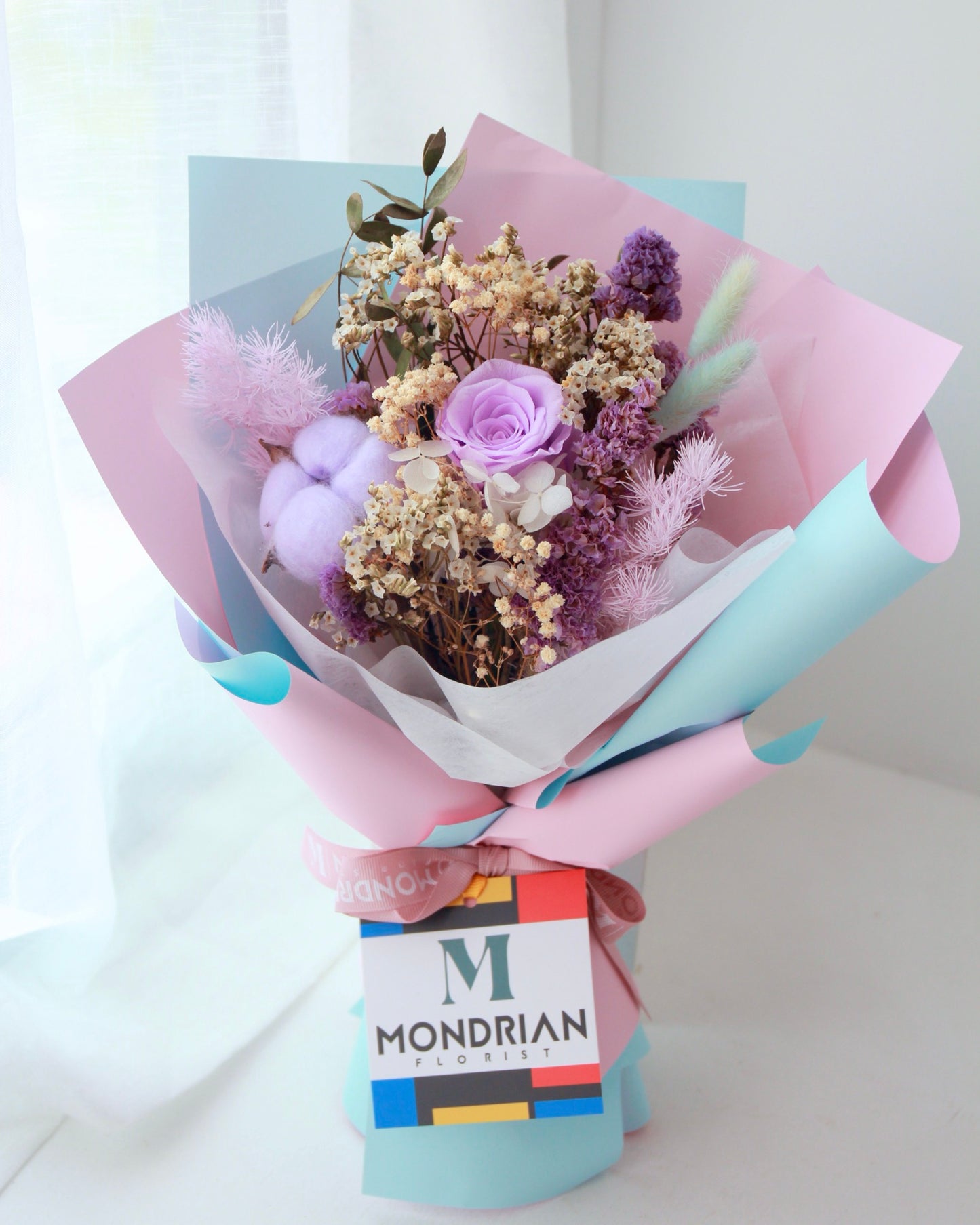 a flower bouquet with preserved light purple rose and cotton flower
