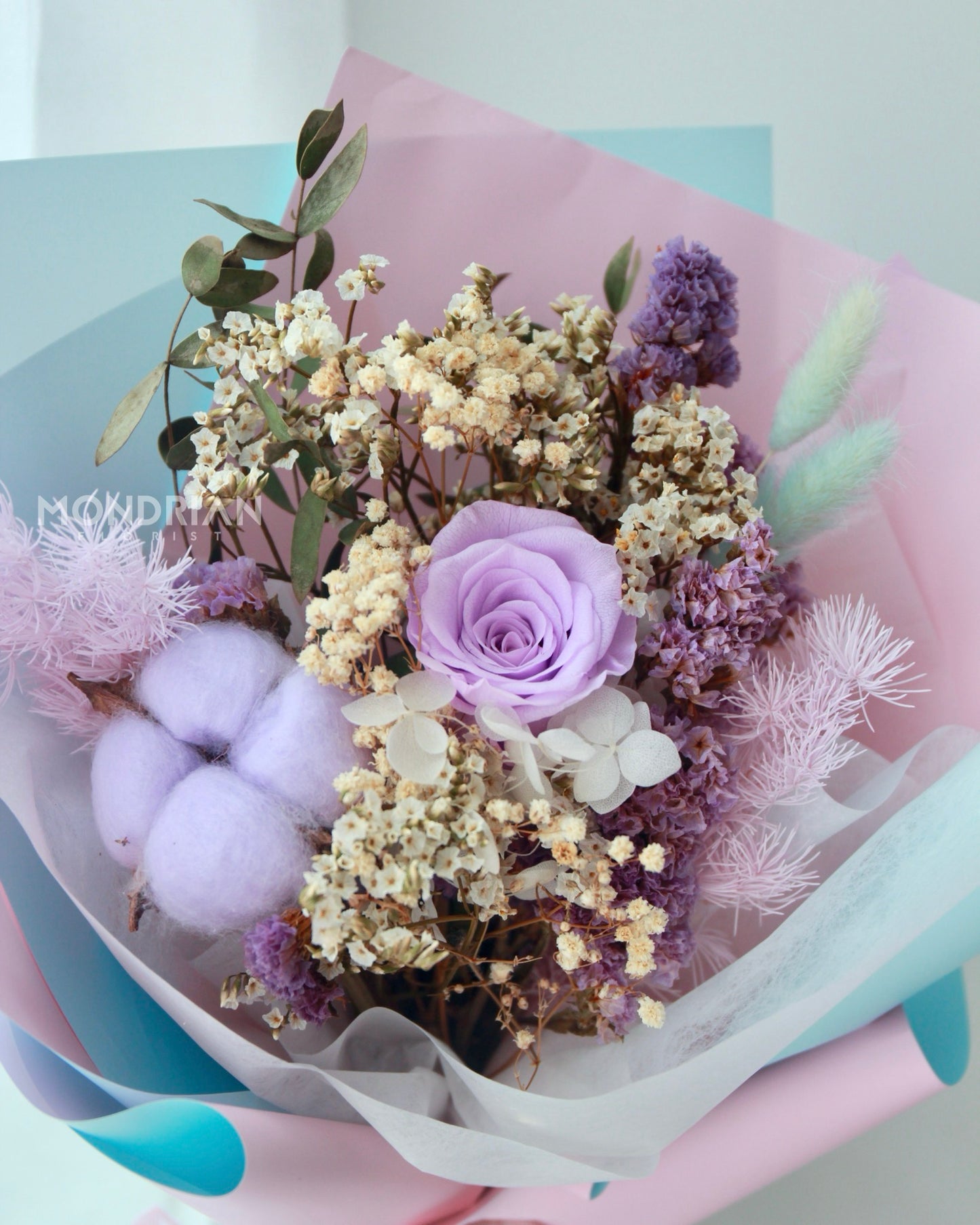 a flower bouquet with preserved light purple rose and cotton flower