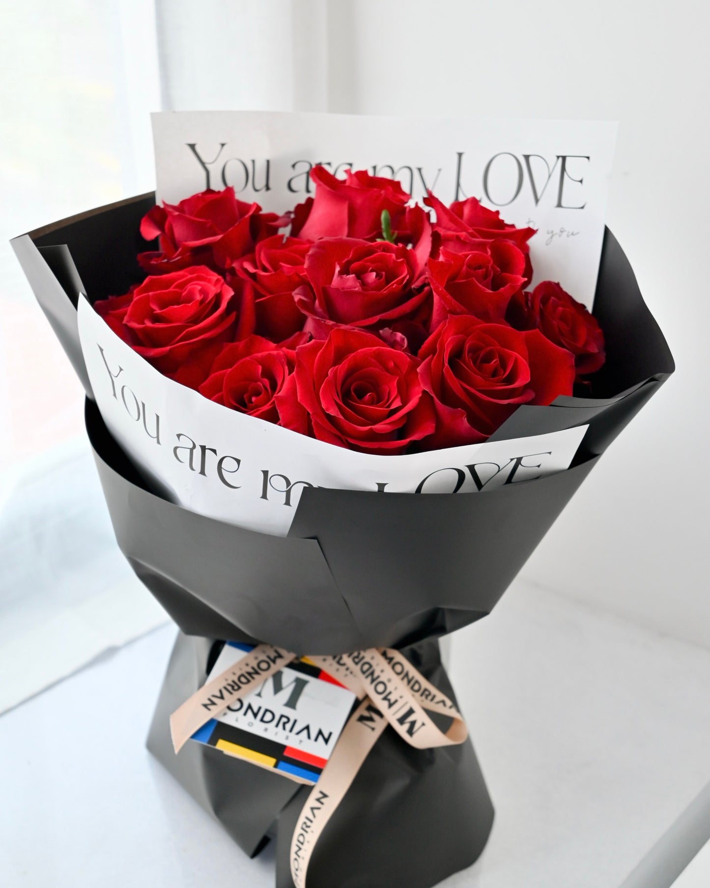 a flower bouquet with 12 stalks of kenya red roses in black wrapping paper