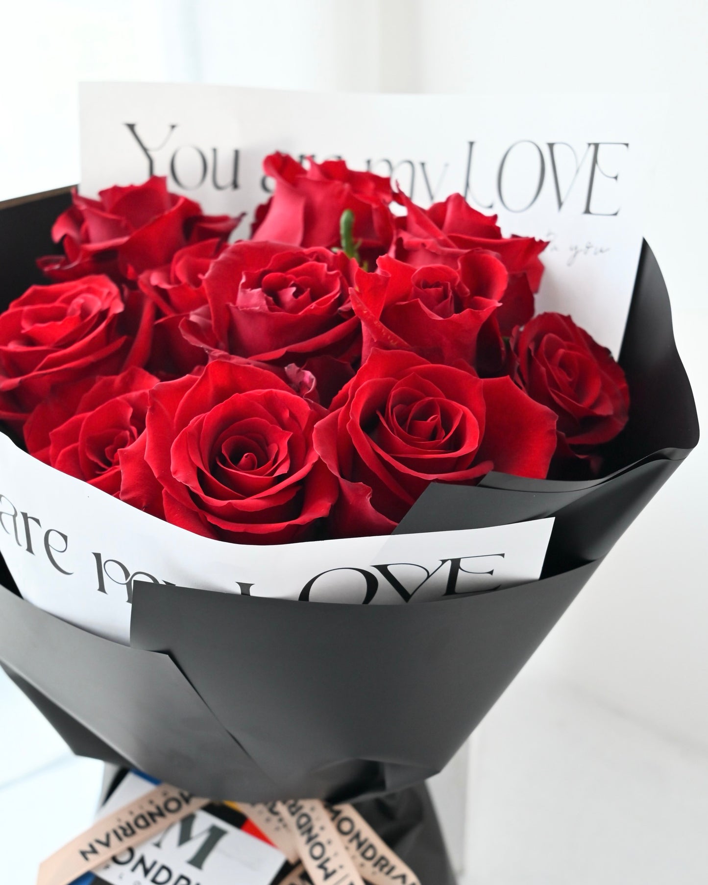 a flower bouquet with 12 stalks of kenya red roses in black wrapping paper