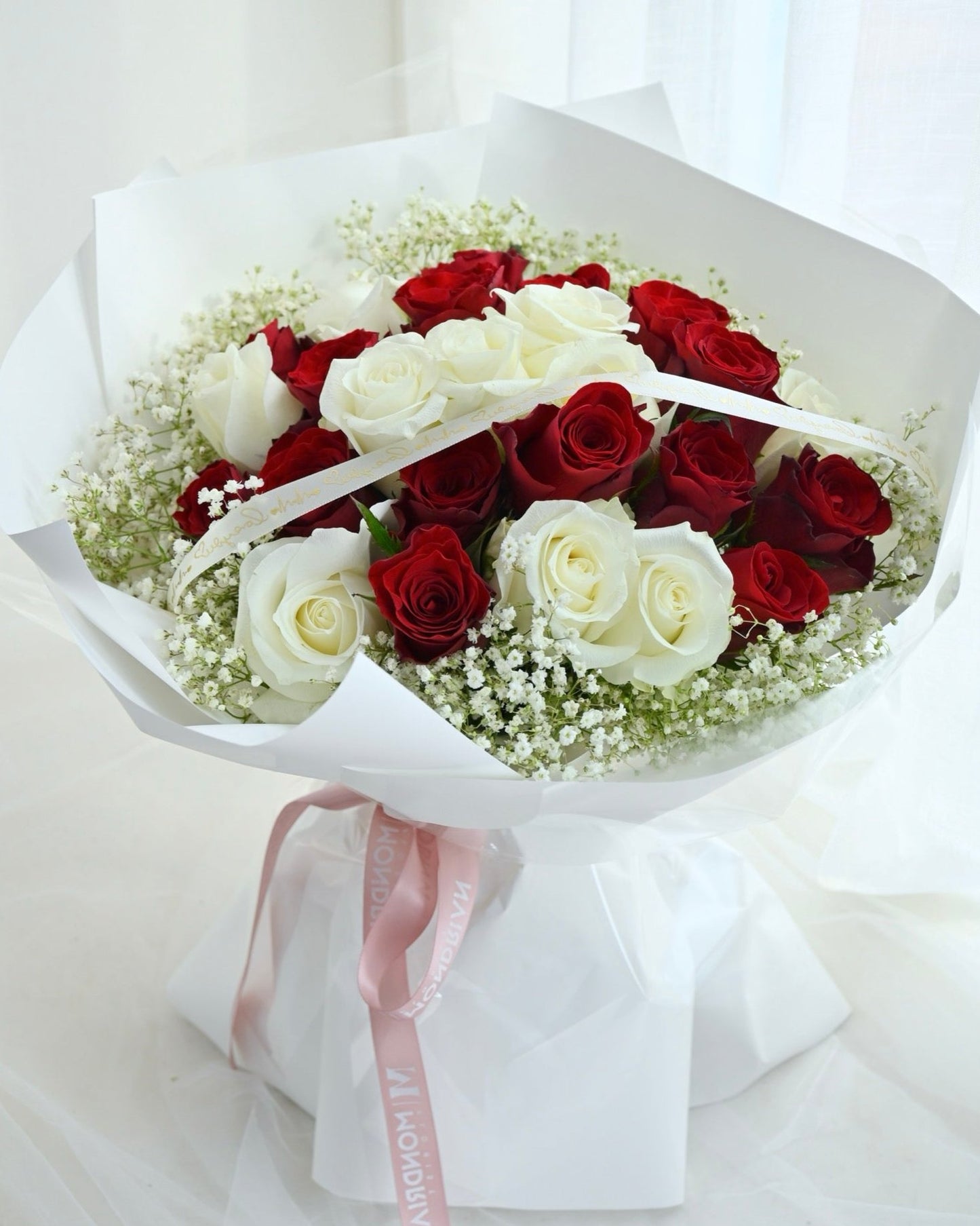 a bouquet of mixed red and white roses with baby's breath by Mondrian Florist