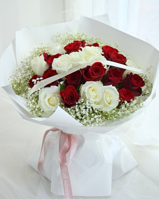 a bouquet of mixed red and white roses with baby's breath by Mondrian Florist