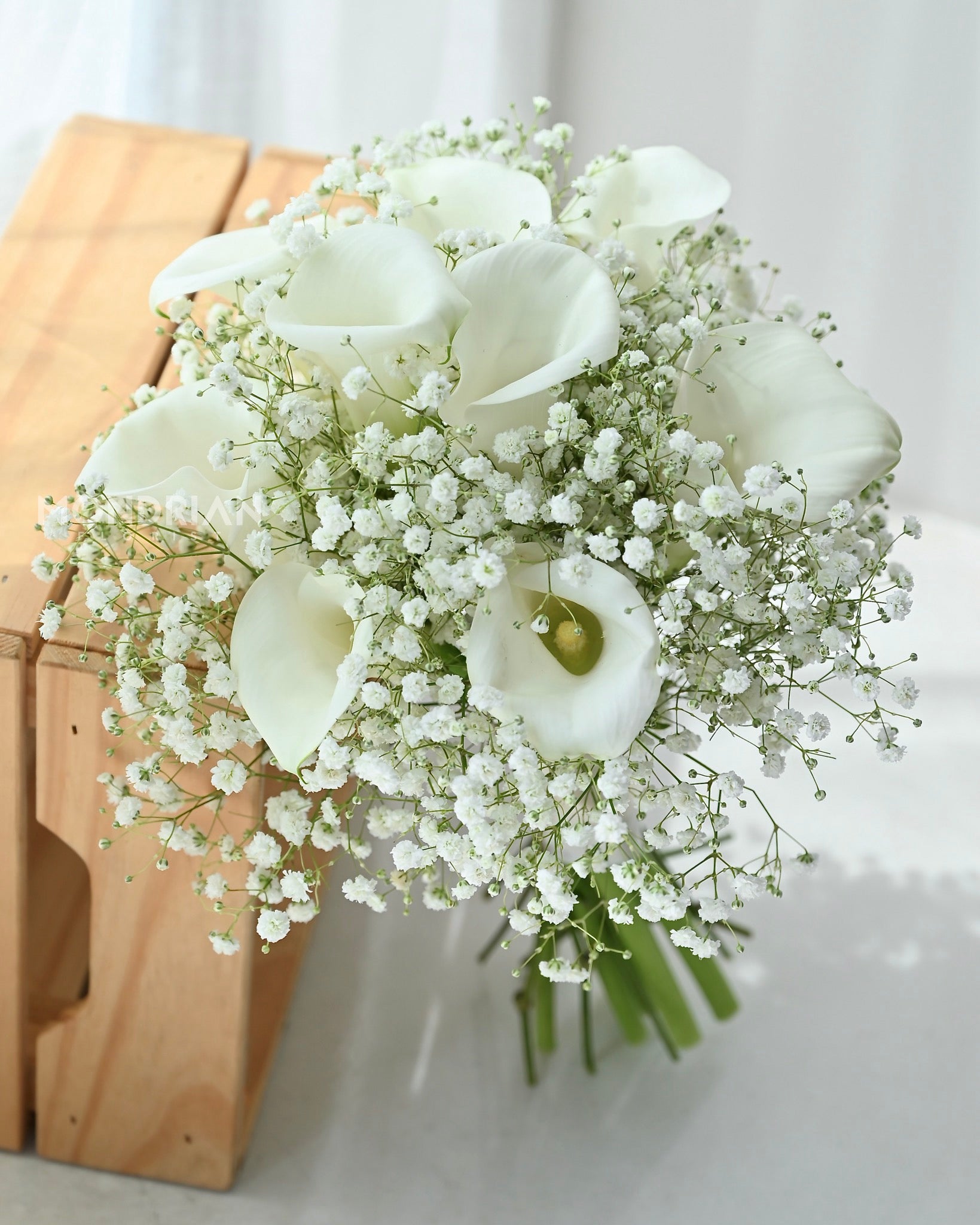 a bridal hand bouquet with fresh calla lily and baby"s breath flower