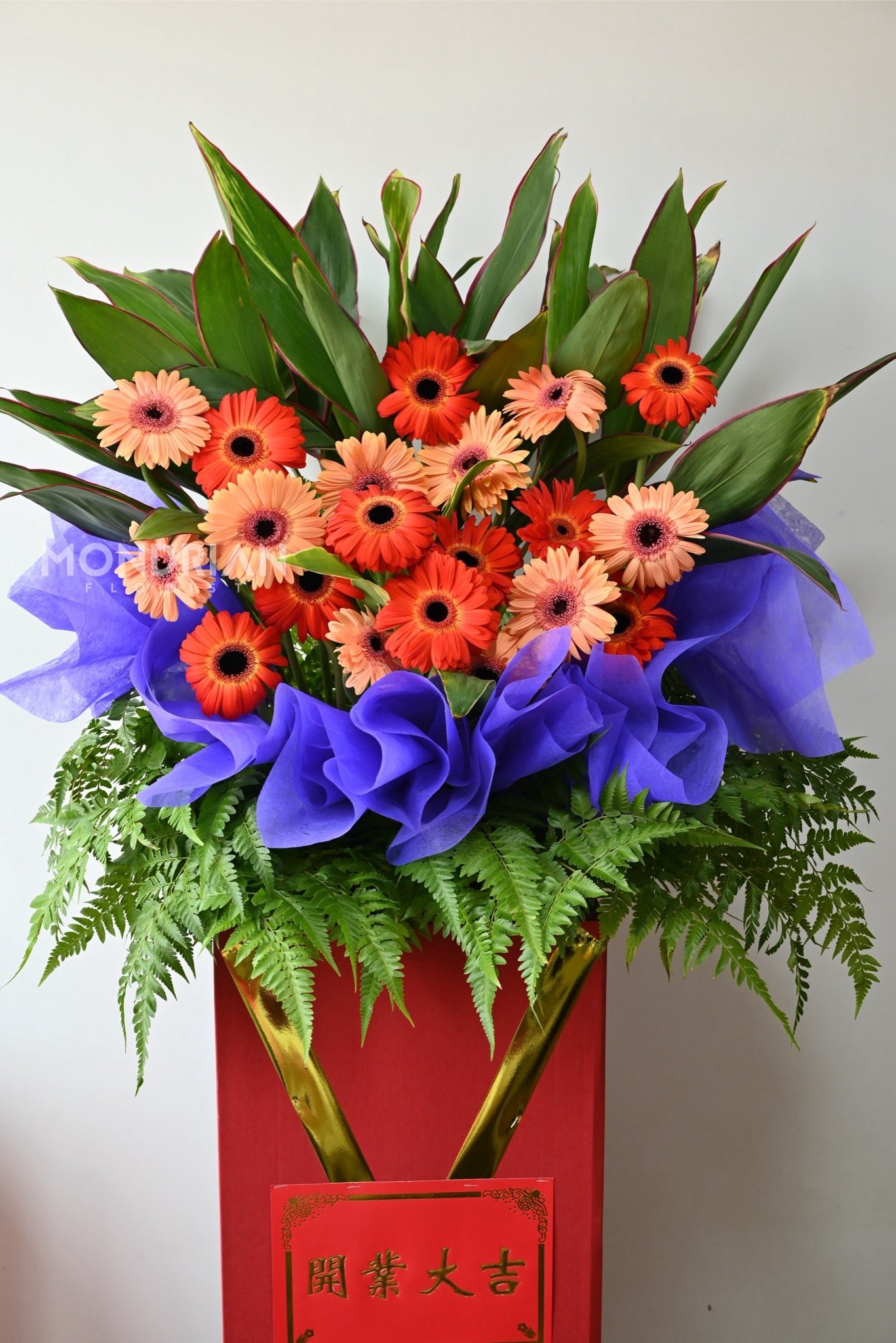 a classic gran opening flower stand with red and orange gerbera flowers and green foliages