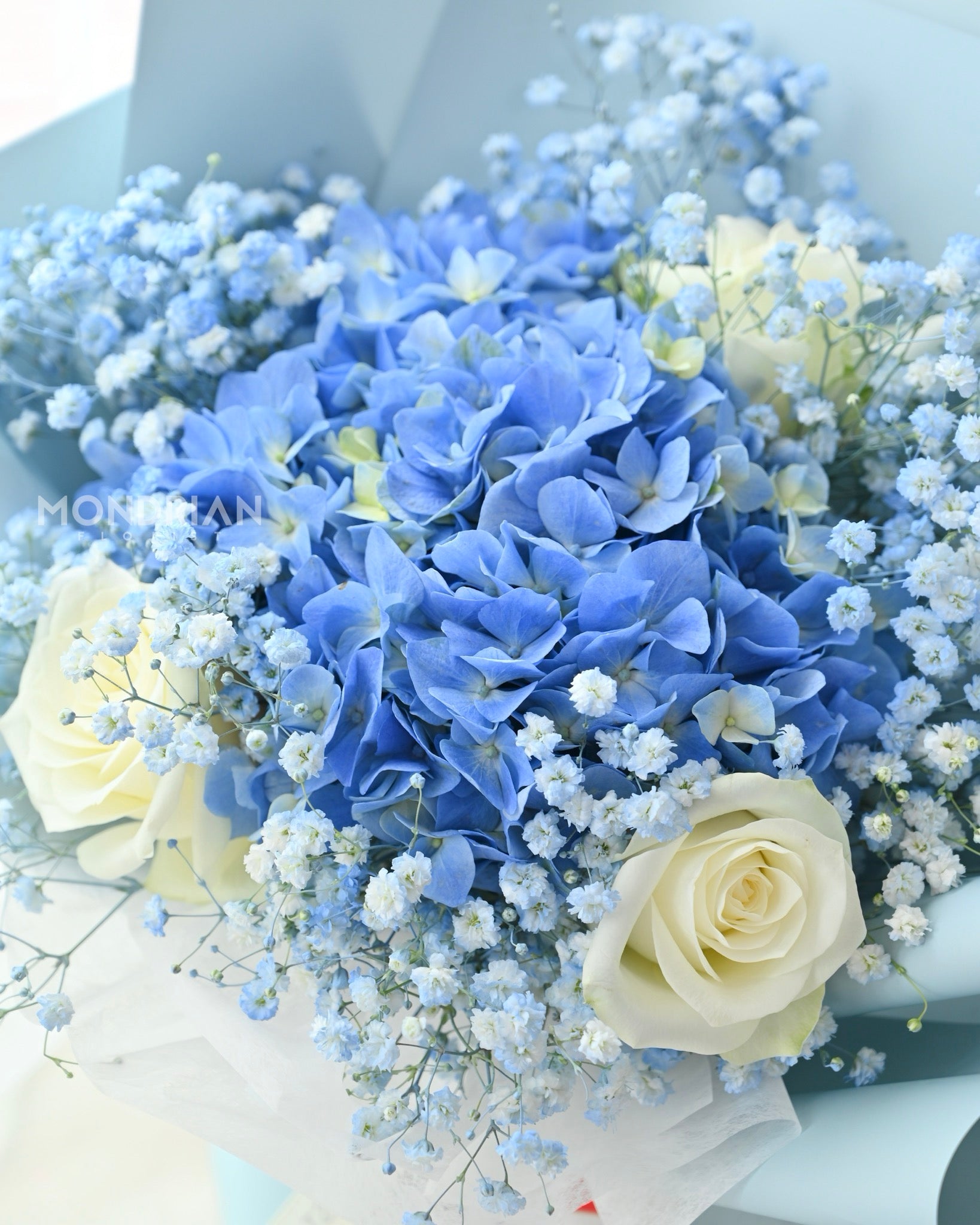a fresh flower bouquet with blue hydrangea, white roses and baby's breath