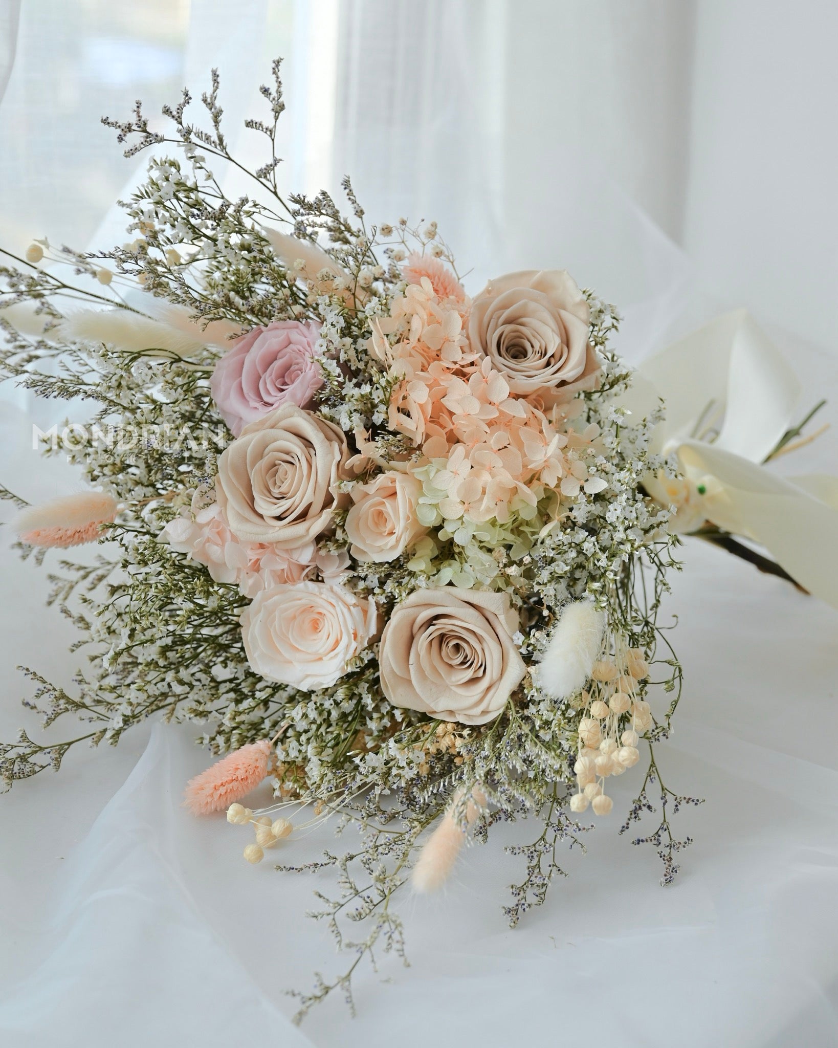 A bridal bouquet made with preserved roses and dried flowers in pastel hue.
